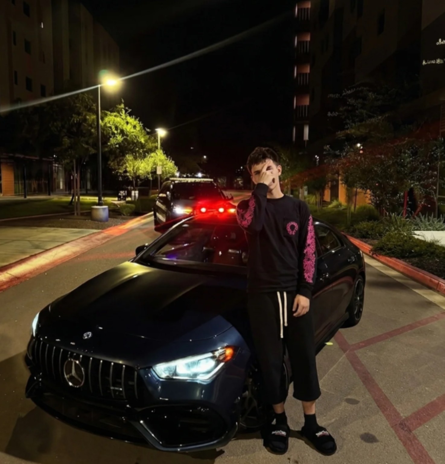 LULPK3X posing in front of a car on a city street at night